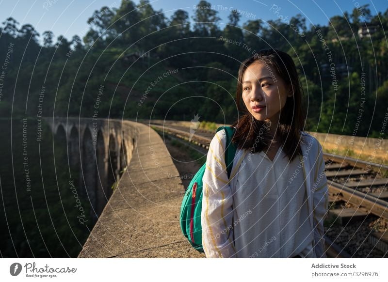 Thoughtful Asian woman walking along railway in old ancient bridge green forest thoughtful asian nine arches bridge shabby ella sri lanka touristic travel