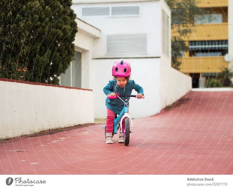 Little girl riding bicycles child ride yard street city roller skates safety protection helmet path building exterior summer season lifestyle rest relax kid