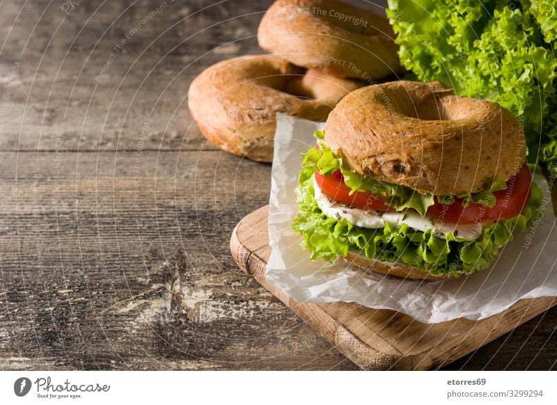Vegetable bagel sandwich on wooden table Bagel Sandwich Food Healthy Eating Food photograph Meal Tomato Mozzarella Lettuce Cheese Snack Vegetarian diet