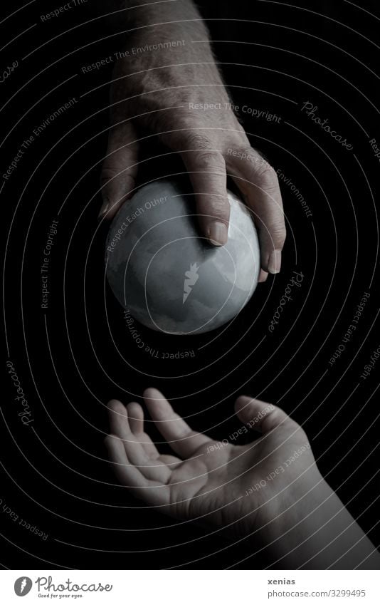 mature hand gives grey globe to young hand Hand Fingers Environment Earth Climate Climate change Gray Black Responsibility Fear of the future
