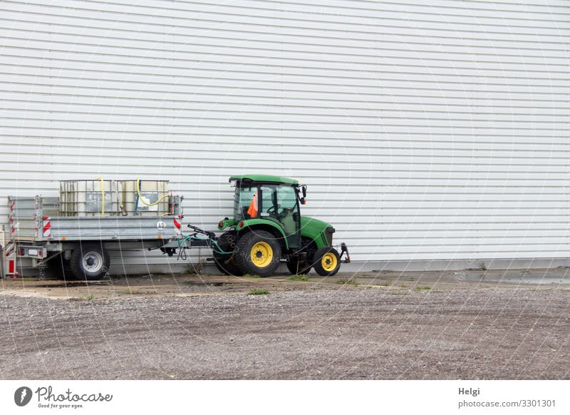 Tractor with trailer standing in front of a white wall Port City Places Facade Trailer Stone Metal Plastic Stand Wait Authentic Uniqueness Brown Yellow Gray