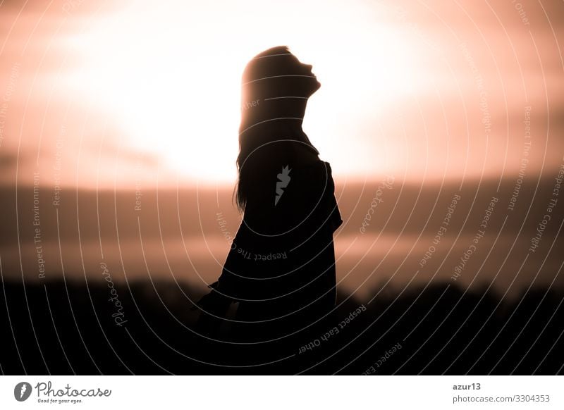 Youth woman soul at golden sun meditation awaiting future times. Silhouette in front of sunset or sunrise in summer nature. Symbol for healing burnout therapy, wellness relaxation or resurrection.