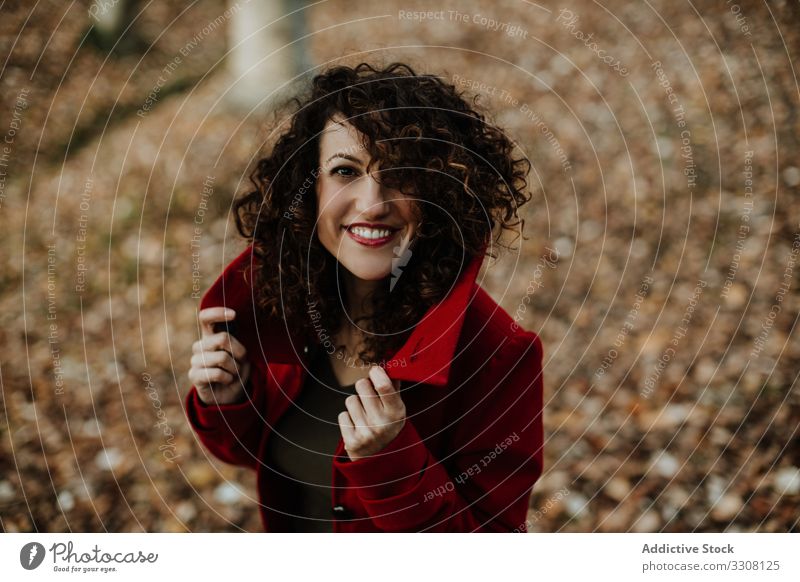 Satisfied elegant lady in coat amid fallen leaves in woods woman forest autumn fun park nature laugh smile enjoy female young casual curly season lifestyle