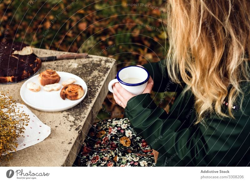 Faceless lady having picnic in park woman sitting table drinking milk cup mug rural autumn female pastry bakery cake sweet pie grass homemade fresh dessert food