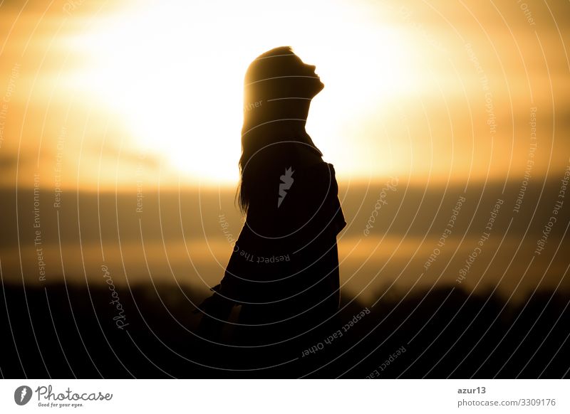 Youth woman soul at orange sun meditation awaiting future times. Silhouette in front of sunset or sunrise in summer nature. Symbol for healing burnout therapy, wellness relaxation or resurrection.
