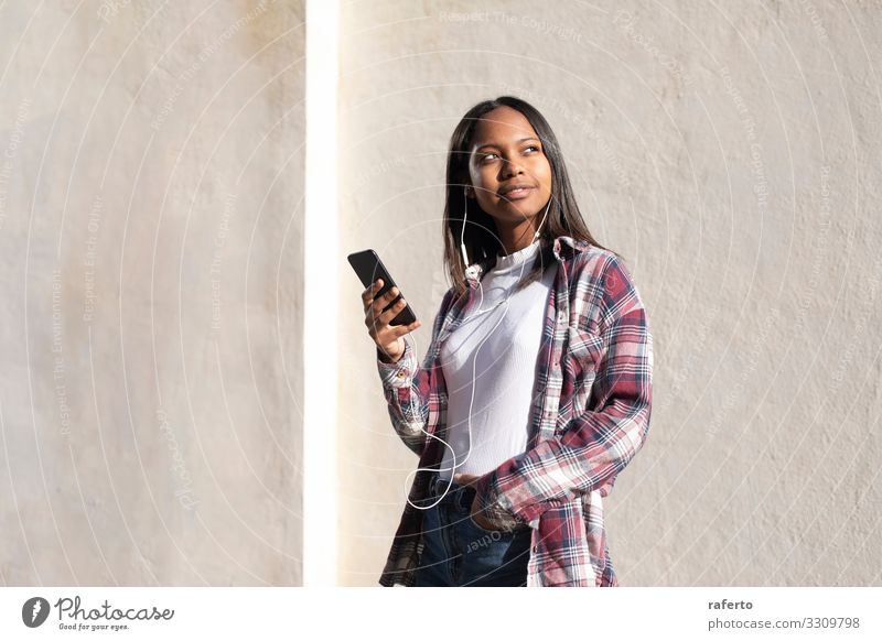 Portrait of African American young woman standing on the street while using a mobile phone Lifestyle Happy Beautiful Telephone PDA Technology Internet