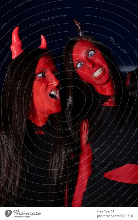 Two women in a devil costume at Halloween making funny faces Elegant Beautiful Playing Hallowe'en Woman Adults Fashion Clothing Dress Suit Boots Thin Eroticism