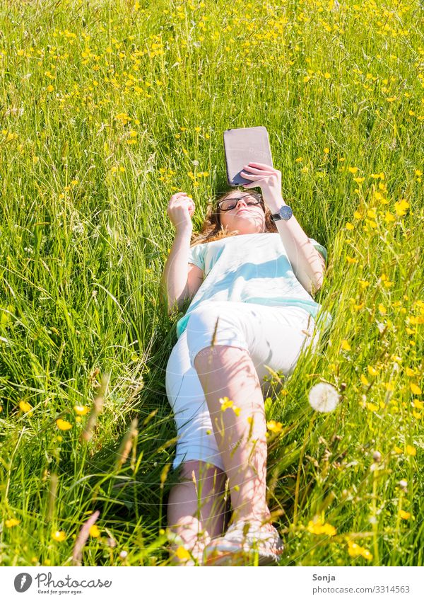 Young woman with e-book lies in a meadow Lifestyle Leisure and hobbies Reading Study E-Book Entertainment electronics Feminine Youth (Young adults) 1