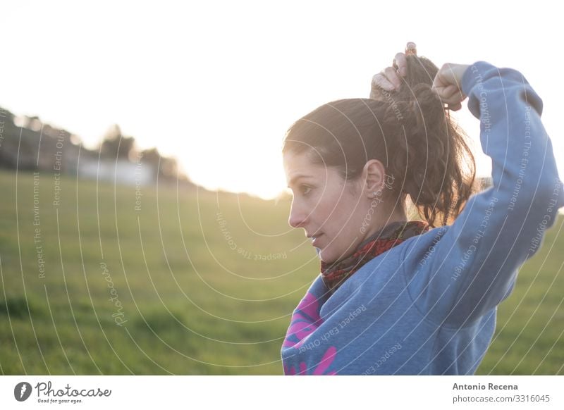 Woman makes a pigtail at sunset before running Sports Human being Feminine Adults Stand Ponytail Sunset real people realistic candid Spanish sportswoman 30s 40s