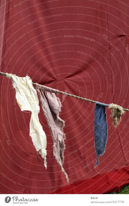 Three flags in white, grey and blue flutter merrily on a rope, tied in the wind, in front of a red canvas tarpaulin at an event. Festive Hang Design Decoration