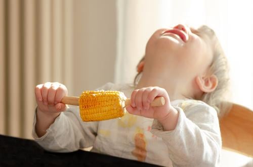 Child holds maize in his hand and throws his head back crying Food Vegetable Maize Corn cob Eating Human being Feminine Toddler girl 1 1 - 3 years To hold on