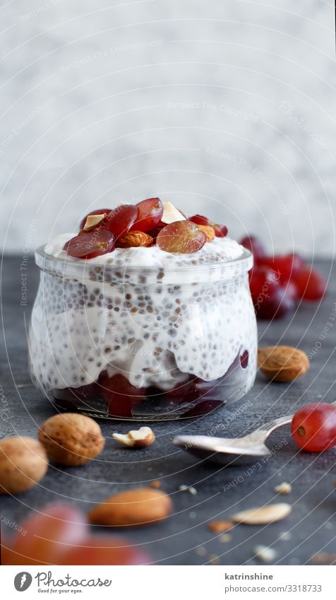 Chia pudding parfait with red grapes and almonds Yoghurt Fruit Dessert Eating Breakfast Diet Spoon Dark Gray White jar chia Bunch of grapes nuts Pudding seed