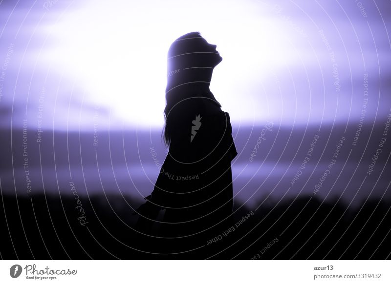 Youth woman soul at purple sun meditation awaiting future times. Silhouette in front of sunset or sunrise in summer nature. Symbol for healing burnout therapy, wellness relaxation or resurrection.