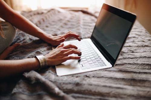 Woman's hands typing on laptop keyboard in the cozy bedroom. Lifestyle Academic studies Work and employment Profession Workplace Office Financial Industry