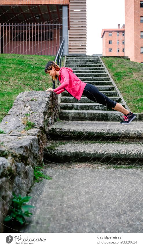 Female athlete doing push-ups outdoors Happy Body Sports Human being Woman Adults Grass Sneakers Fitness Thin Natural sportswoman supported wall stairs urban