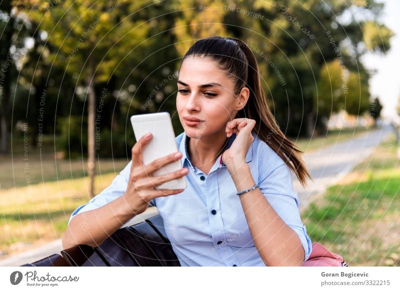 Pretty young sitting on a bench with mobile phone Lifestyle Happy Beautiful Summer Sun Telephone PDA Technology Human being Young woman Youth (Young adults)