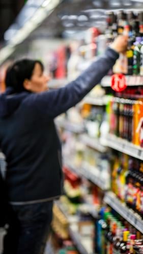 Woman looks at the goods on a supermarket shelf Shopping Trolley Food Supermarket Colour photo Consumption Store premises Human being consumer by hand