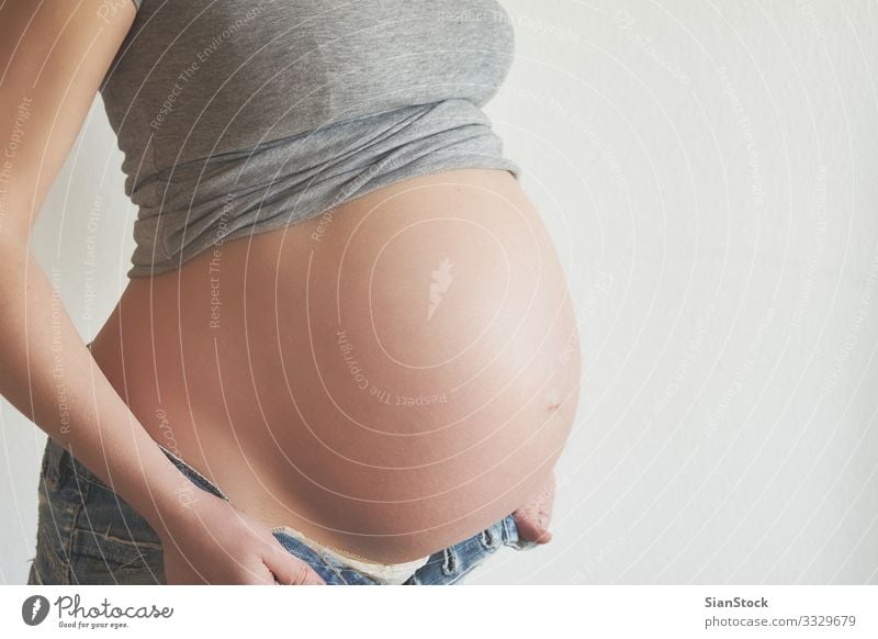 Pregnant woman trying to wear her jeans Lifestyle Happy Beautiful Body Human being Baby Woman Adults Mother Hand Touch Love Sit White pregnancy belly Home