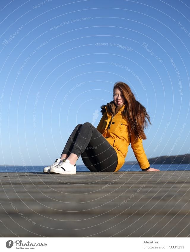 Young woman sitting on a jetty by the sea Lifestyle Joy Beautiful Well-being Vacation & Travel Trip Ocean Footbridge Wooden floor Youth (Young adults)