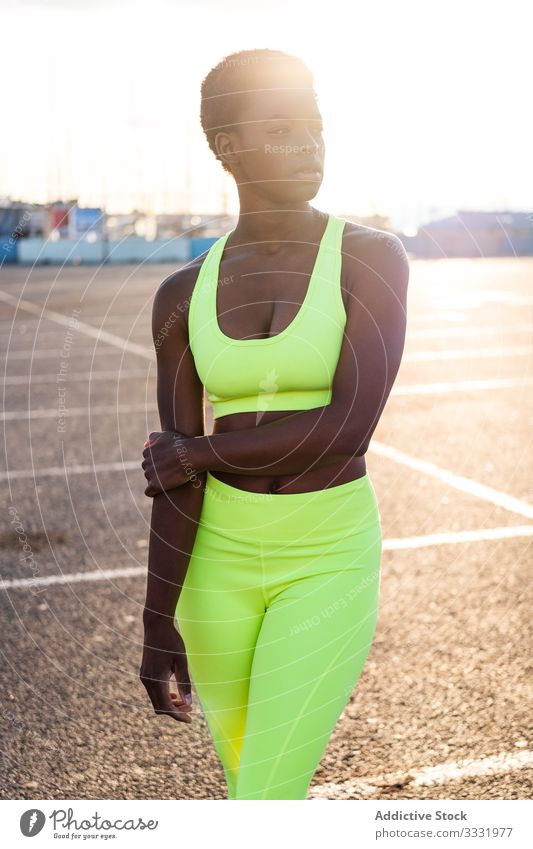 Confident ethnic sportswoman before training on sports ground during sunset confident motivation street focus serious physique slim aspiration athletic