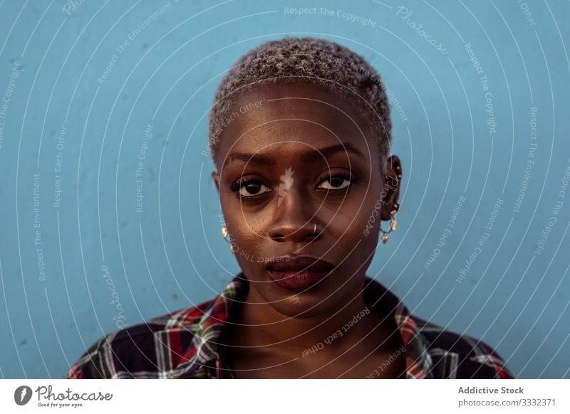 Young black short haired woman looking at camera with intense look female sad portrait challenge piercing plaid shirt african american young unhappy upset