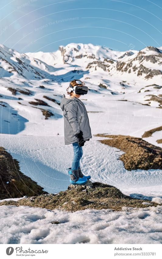 Excited boy in VR headset having fun in snowy mountains vr explore winter excited resort kid child outwear goggles glasses device gadget virtual reality