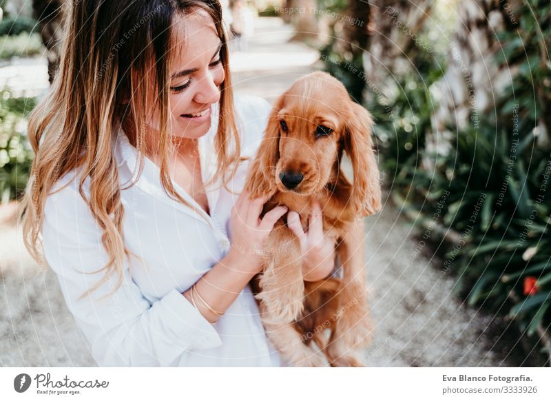 young woman and her cute puppy of cocker spaniel outdoors in a park Woman Dog Pet Park Sunbeam Exterior shot Love Embrace Smiling Rear view Kissing Breed