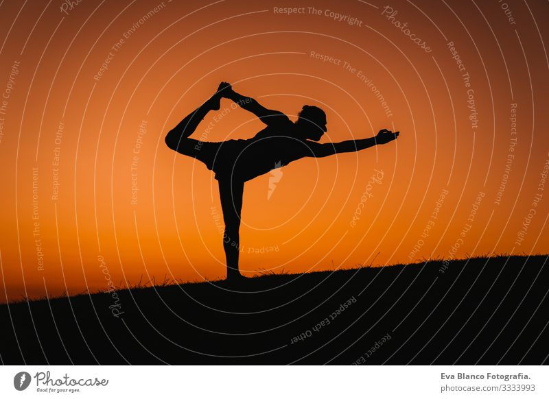silhouette of young man in a park doing yoga sport. orange sky background. healthy lifestyle. Silhouette Back-light Concentrate Position Human being