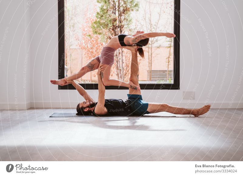 young couple Couple practicing acro yoga by the window in studio or gym. Healthy lifestyle Yoga Sports Gymnasium indoor Man Power Human being