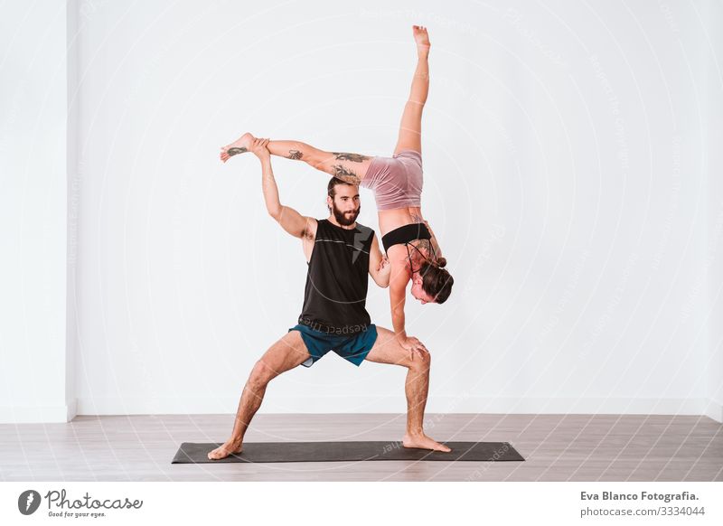young couple Couple practicing acro yoga in white studio or gym. Healthy lifestyle Yoga Sports Gymnasium indoor Man Power Human being human relationships