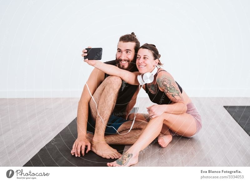 two friends at the gym taking a selfie with mobile phone and headset and having fun. Sport and technology concept Couple Friendship Youth (Young adults) Man
