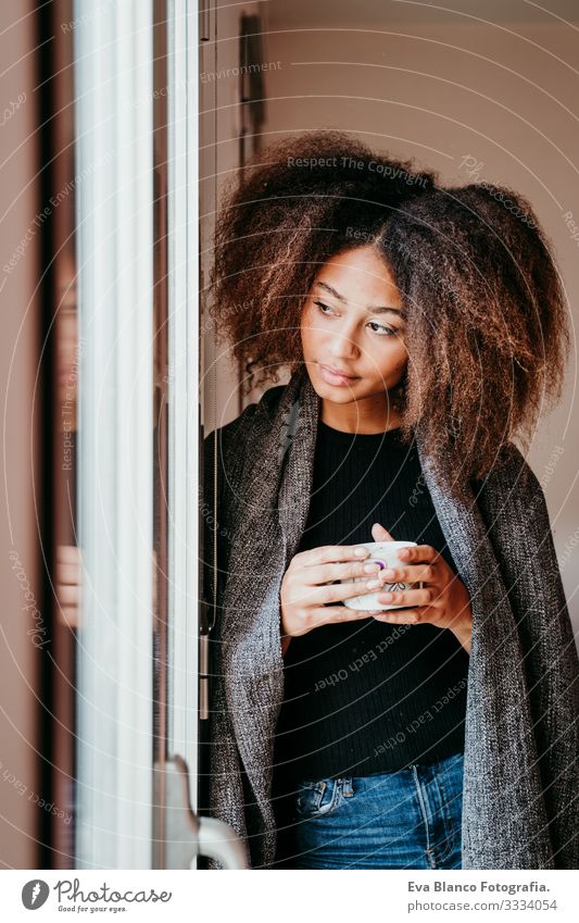 portrait of beautiful afro american young woman by the window holding a cup of coffee. Lifestyle indoors African-American Woman Coffee Home Ethnic
