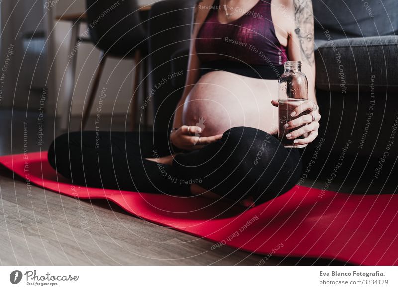 young pregnant woman at home practicing yoga sport and drinking water, healthy lifestyle Pregnant Woman Yoga Home Sports Healthy Lifestyle Youth (Young adults)