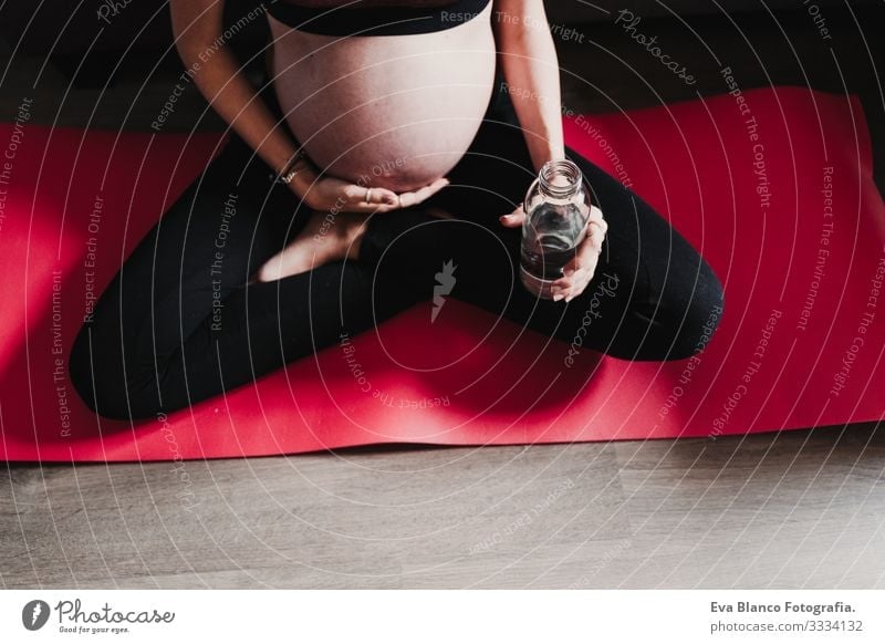 young pregnant woman at home practicing yoga sport and drinking water, healthy lifestyle Pregnant Woman Yoga Home Sports Healthy Lifestyle Youth (Young adults)