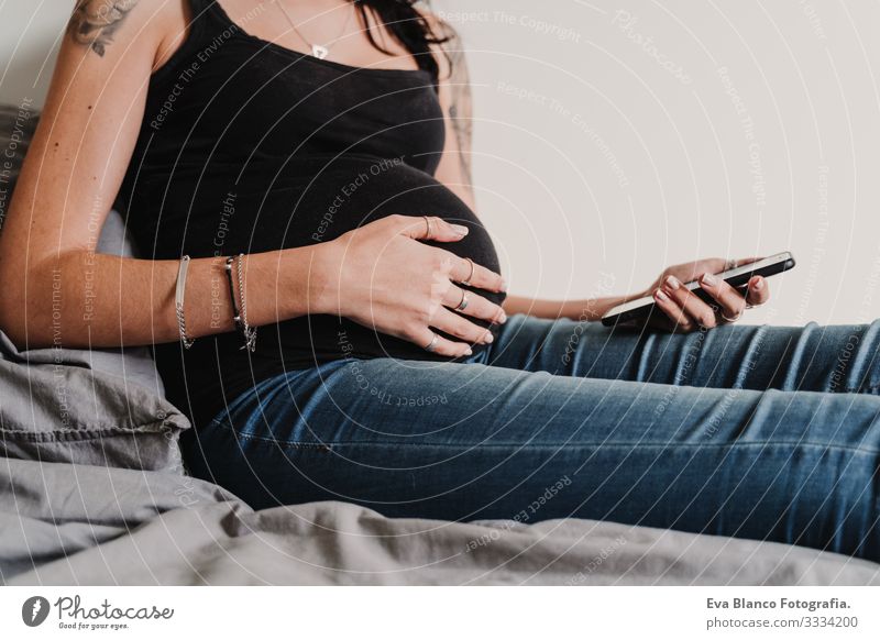 young pregnant woman at home using mobile phone Pregnant Woman Cellphone Technology Home Bed PDA expecting Baby Showing one's bellybutton Internet wifi Writing