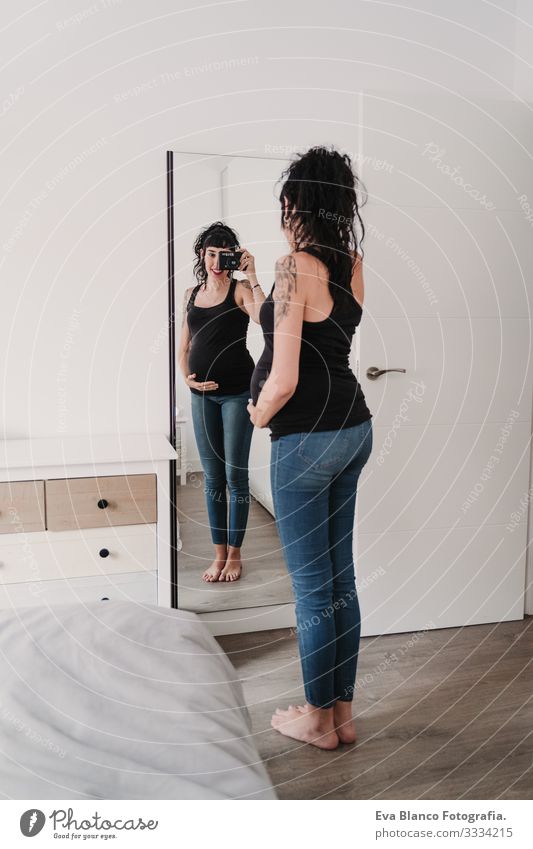 young pregnant woman at home taking a selfie on mirror with camera Pregnant Woman Illustration Camera Mirror Home Smiling Happy Portrait photograph