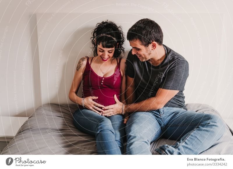 young couple at home hugging. Happy Pregnant woman smiling Couple Love Woman Parents expecting Home Sofa Embrace Kissing parenthood motherhood Husband Wife