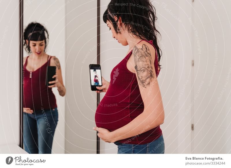 young pregnant woman at home taking a selfie on mirror with mobile phone Cellphone PDA Pregnant Woman Illustration Camera Mirror Home Smiling Happy