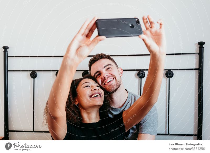 happy couple in love at home. Afro american woman and caucasian man taking a selfie with mobile phone. ethnic love concept Couple Love African-American Ethnic