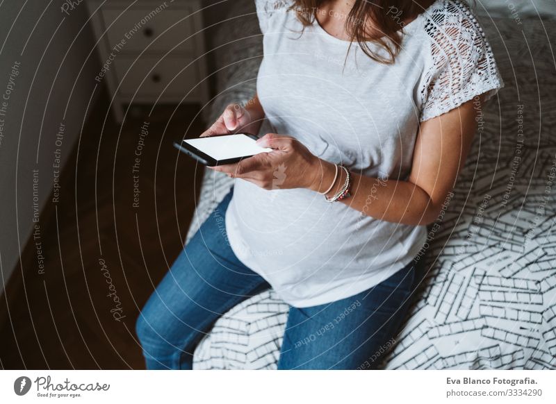 young pregnant woman at home using mobile phone Pregnant Woman Home Cellphone Technology PDA Smiling Showing one's bellybutton Fat Baby expecting