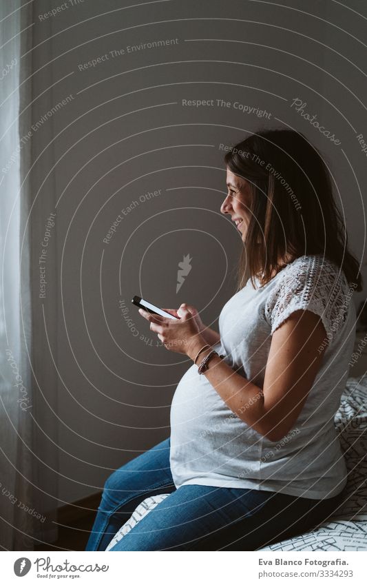 young pregnant woman at home using mobile phone Pregnant Woman Home Cellphone Technology PDA Smiling Showing one's bellybutton Fat Baby expecting