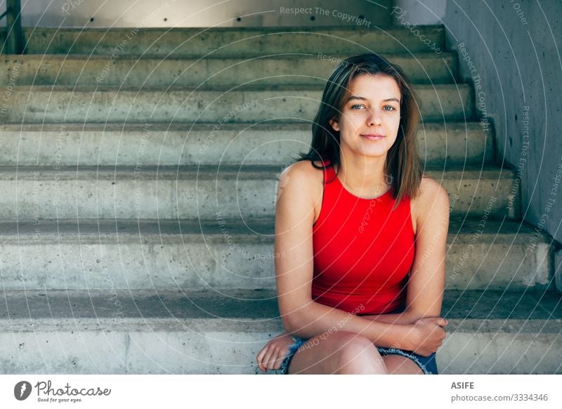 Portrait of a beautiful and confident teen girl in red top and denim skirt sitting on the stairs outdoors smiling Lifestyle Happy Beautiful Summer