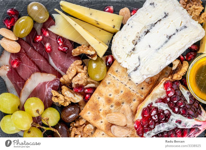 Food Platter With Truffle Cheese, Duck Breast, Brie Cheese, Pecan Nuts, Pomegranate Seeds, Grapes, Almonds, Honey, Olives and Crackers crackers almonds