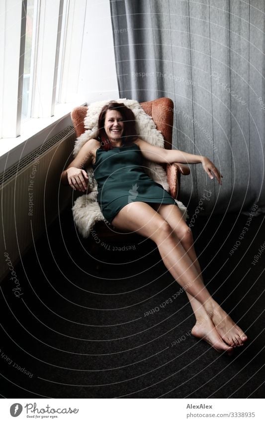 Young, long-legged woman lying in an armchair, laughing Style Joy already Life Living or residing Flat (apartment) Armchair Young woman Youth (Young adults)