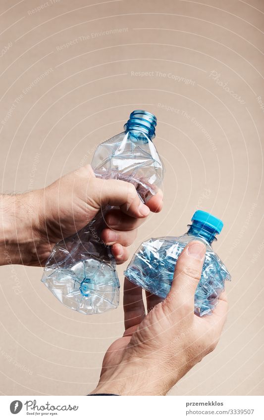 Male hand holding squashed plastic bottle Bottle Save Man Adults Hand Environment Container Plastic Blue Environmental pollution Trash garbage recycle Recycling