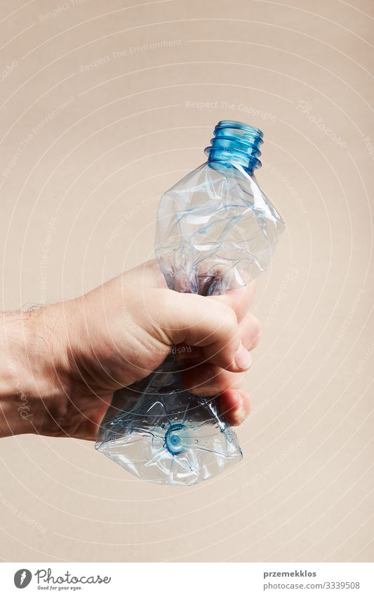 Male hand holding squashed plastic bottle Bottle Save Man Adults Hand Environment Container Plastic Blue Environmental pollution Trash garbage recycle Recycling