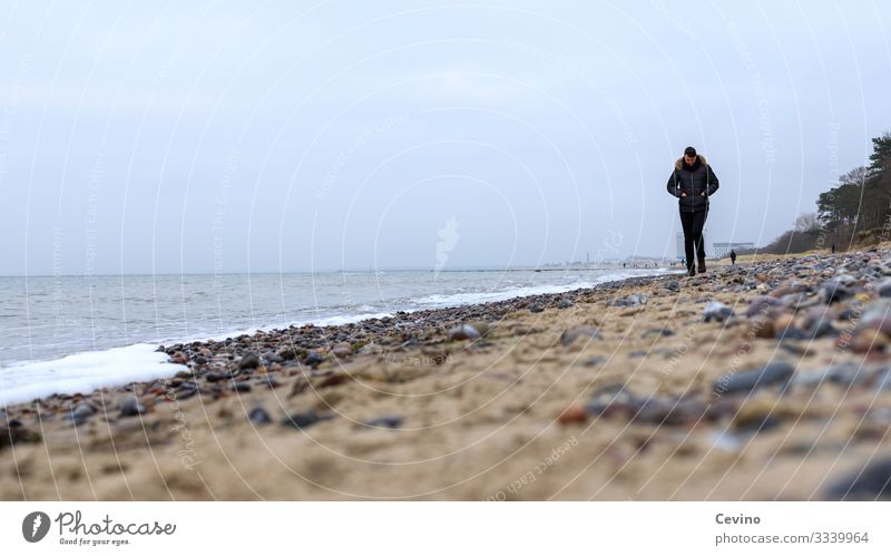 Young man strolls on the beach To go for a walk Beach Baltic Sea Lonely Loneliness thoughts vacation Waves stones Sand hike lost in thought brood young adult
