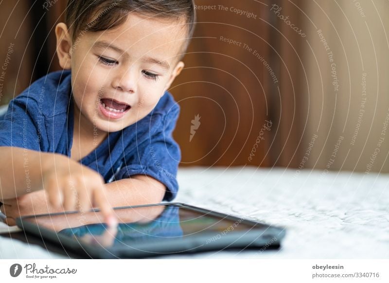 cute young mixed race boy playing with an electronic device Joy Happy Playing Reading Summer Garden Bedroom Child Computer Technology Internet Human being