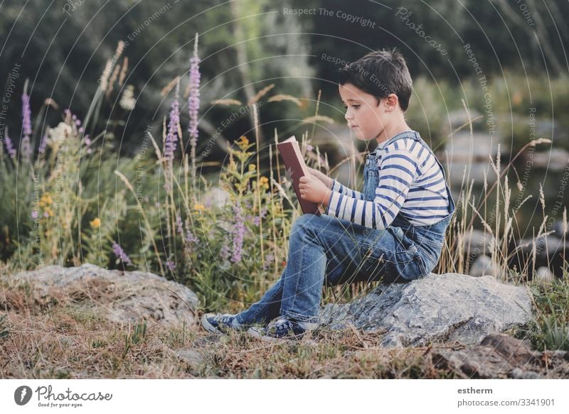 Child sitting reading a book in the field Lifestyle Leisure and hobbies Reading Summer Study Human being Masculine Boy (child) Infancy 1 8 - 13 years Book