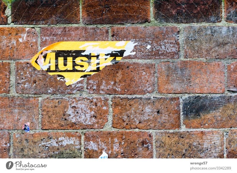 Fragments of posters on a brick wall with the word music Wall (barrier) Brick wall Poster Scrap of paper Wall (building) Colour photo Exterior shot Deserted